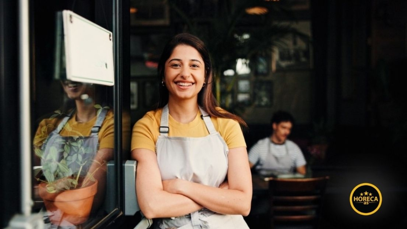 Nasmejana konobarica ispred kafića spremnog za rad