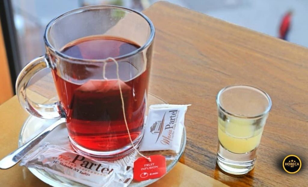 Šolja čaja sa kesicom čaja i dodatkom meda ili limuna na stolu