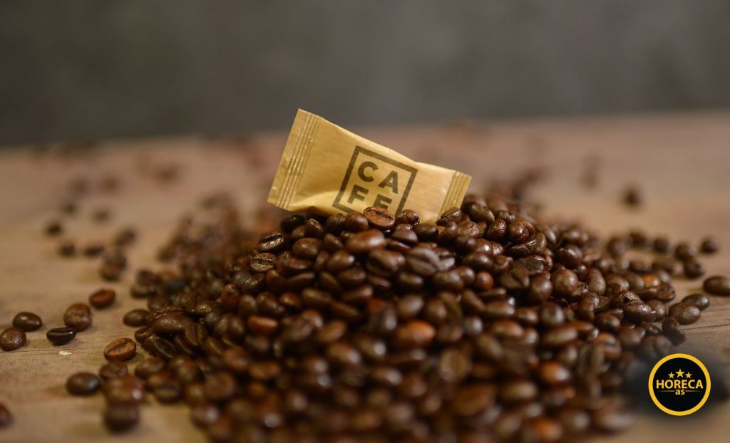 Kesica reklamnog šećera sa logotipom brenda na zrnu kafe u ugostiteljskom okruženju