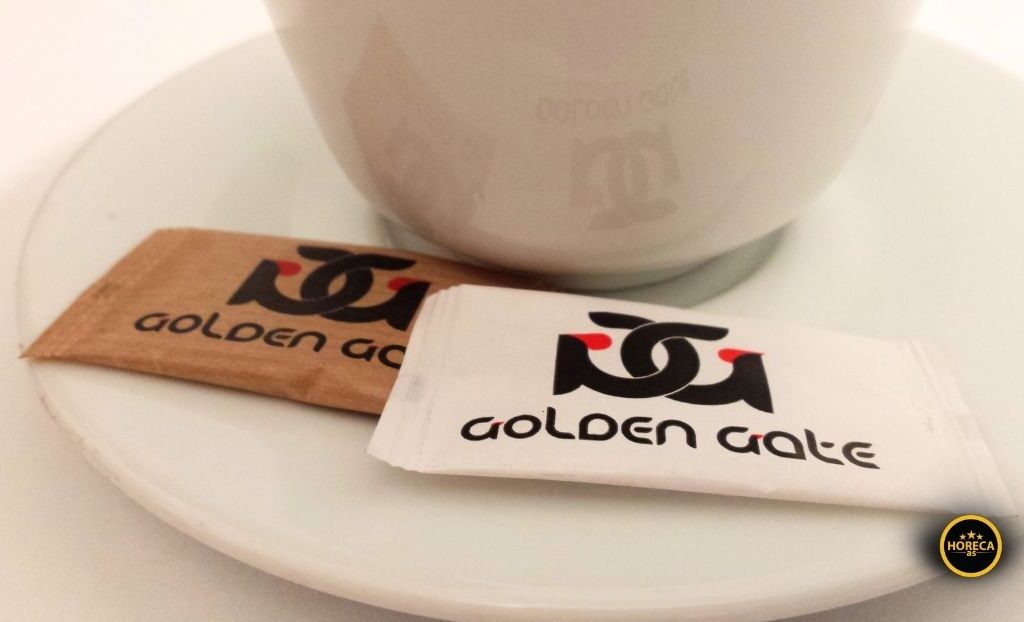 Pakovanja belog i smeđeg šećera pored šoljice kafe na tacni