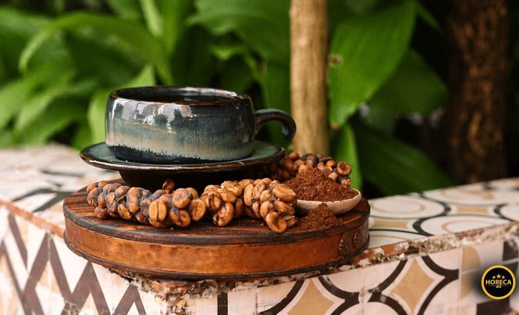 Šolja kafe okružena zrnima Kopi Luwak na rustičnoj podlozi u prirodnom okruženju