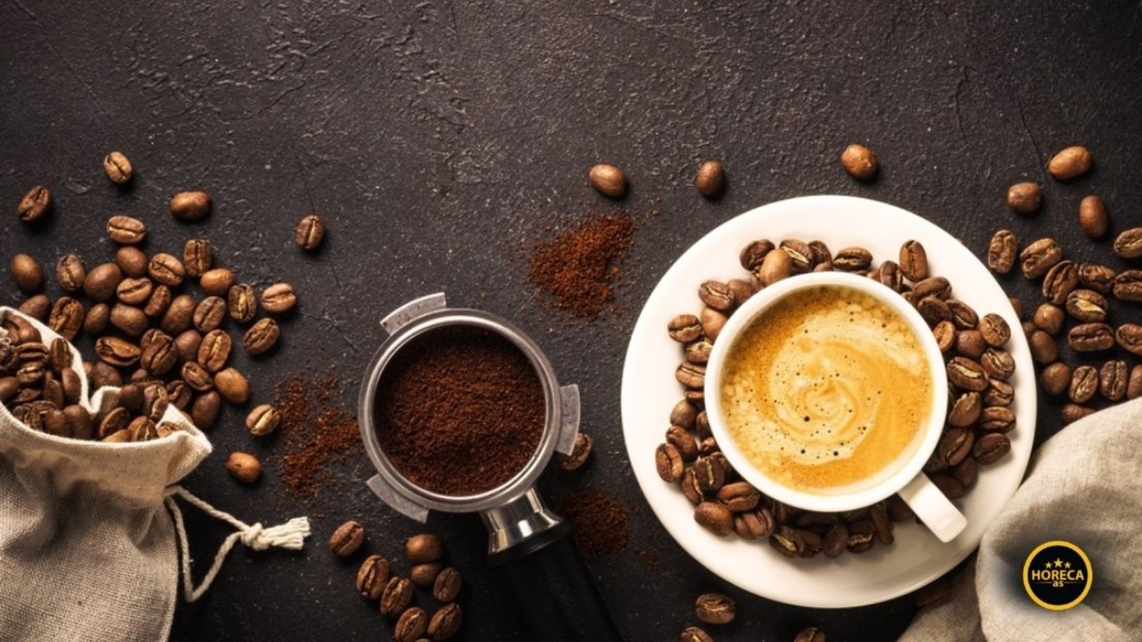 Šolja espresa okružena zrnima kafe i mlevenom kafom na tamnoj podlozi simbolizuje premium kvalitet i bogatu aromu