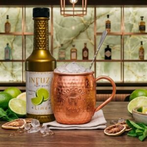INFUZA pire od limete pored Moscow Mule koktela posluženog sa ledom u bakarnoj šolji.