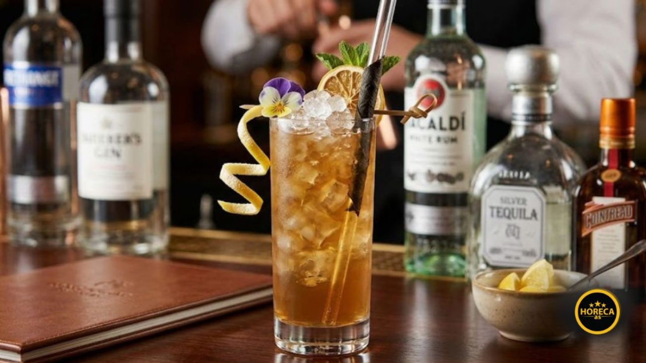 Long Island koktel sa ledom, citrusima i nanom, poslužen u visokoj čaši na šanku.