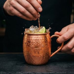 Barmen meša Moscow Mule koktel sa drobljenim ledom i kriškom limete u bakarnoj šolji.