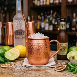 Priprema Moscow Mule koktela sa votkom, ginger beerom, limetom i ledom u bakarnoj šolji.