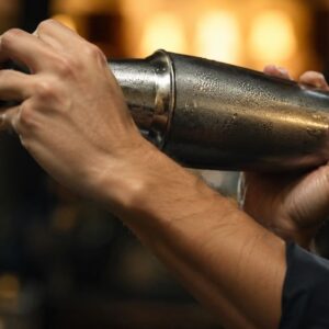 Barmen snažno šejkuje Margarita koktel u metalnom šejkeru.